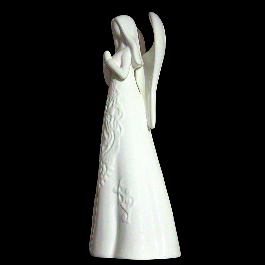 A white ceramic angel figurine with outstretched wings and embossed floral details on its gown, set against a solid black background.