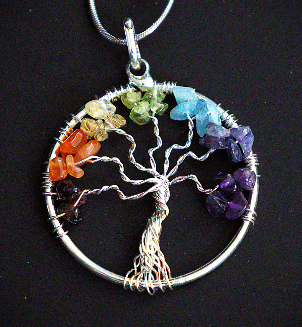 A silver Tree of Life chakra pendant necklace with raw, polished gemstone chips in each of the seven colors, shown on a black background.