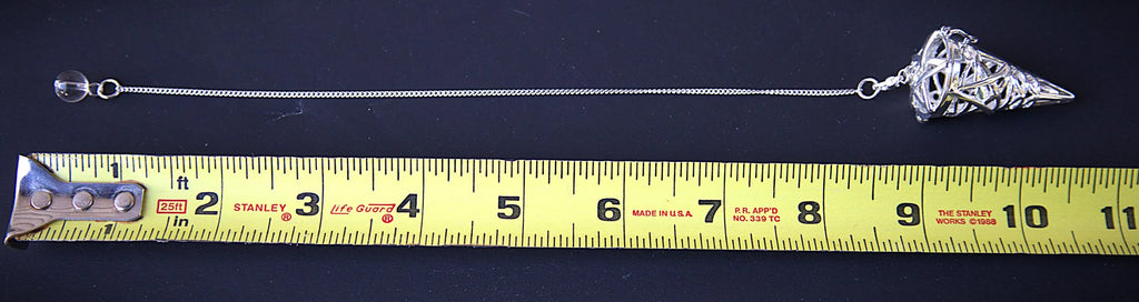 A silver-toned metal chain accessory with a decorative pointed end, laid out on a black background next to a yellow measuring tape to show scale.