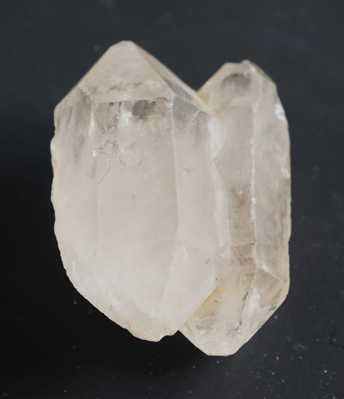 A natural clear quartz crystal cluster with prominent geometric facets, photographed against a solid black background.